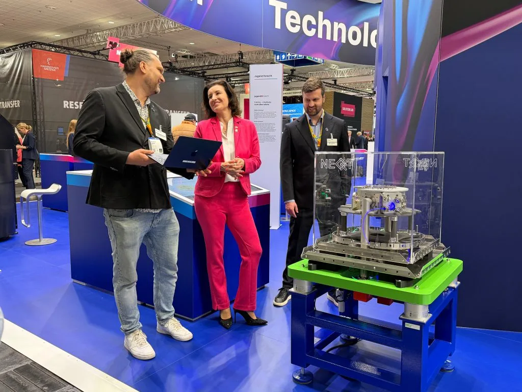 NeQxt representatives at Hannover Messe beside quantum computing equipment